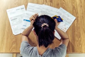 Asian woman holding the head worry about find money to pay credit card debt and all loan bills.