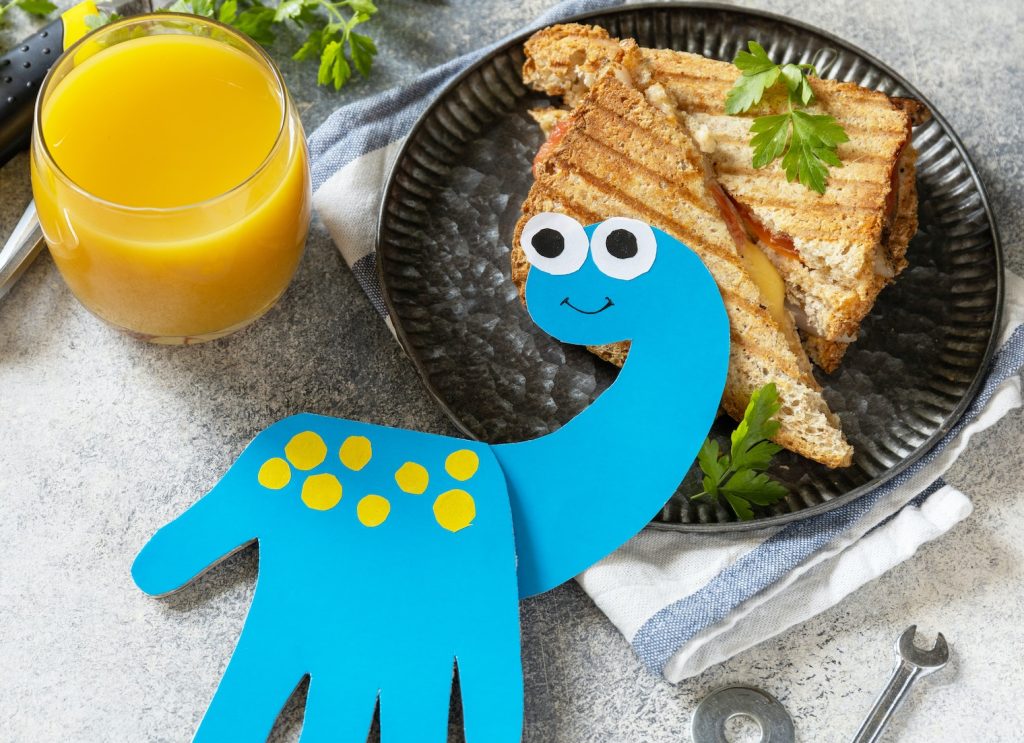 Happy father's Day. Father’s Day card dinosaur and breakfast for dad on grey stone table.